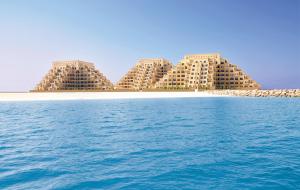 un gruppo di edifici su una spiaggia con acqua di Clarence Apartment a Ras al Khaimah