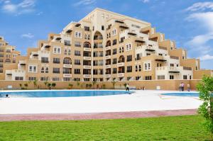 a large building with a pool in front of it at Clarence Apartment in Ras al Khaimah