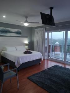 a bedroom with a bed and a tv and a balcony at Sky Holiday House in East London