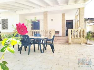 une terrasse avec une table, des chaises et une fleur dans l'établissement Villa Miranda con ampio giardino, à Marina di Mancaversa