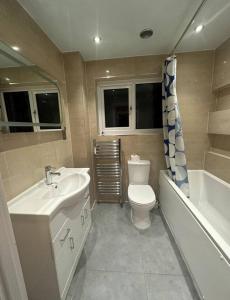 y baño con lavabo, aseo y bañera. en Modern 3 bedroom house- 2 parking spaces- near central MK en Shenley Lodge