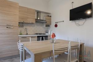 Casa vacanza Lucia Puglia On line في مورتشانو دي ليوكا: مطبخ مع طاولة خشبية مع كراسي وتلفزيون