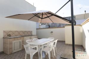 Casa vacanza Lucia Puglia On line في مورتشانو دي ليوكا: فناء به طاولة بيضاء وكراسي ومظلة