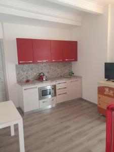 cocina con armarios rojos y microondas de acero inoxidable en happy house fiume veneto 1, en Bannia