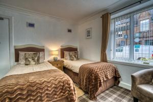 2 camas en una habitación con ventana en Pitfaranne Guest House, en Inverness