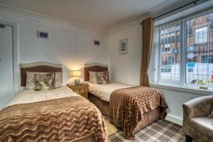 two beds in a room with a window at Pitfaranne Guest House in Inverness