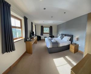 a bedroom with a bed and a desk and a window at Afan Lodge in Port Talbot