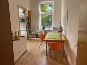 kuchnia ze stołem i pomarańczowymi krzesłami w kuchni w obiekcie Zweibettzimmer Business mit eigenem Bad ( Nichtraucher ) w Hanowerze