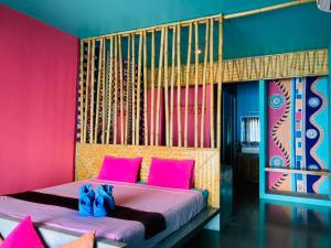 a bedroom with a bed with pink and blue walls at Chaba Bungalows in Ban Ai Dao