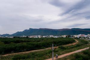 two people walking down a dirt road with mountains in the background at Hotel Sitar Grand in Tirupati