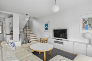 a living room with a couch and a tv and a table at Happy Home Lauttasaari in Helsinki