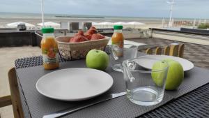 a table with plates and bottles of juice and a bowl of fruit at Escapade face à la mer in Malo-les-Bains