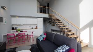 ein Wohnzimmer mit einem Sofa, einer Küche und einer Treppe in der Unterkunft Apartamenty Sun & Snow Bukowa Góra in Wisła