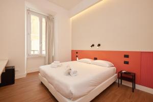 a bedroom with a large white bed with an orange headboard at DEM Hotel in Rome