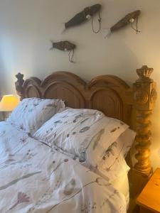 Una cama con cabecero de madera y algunas armas en la pared en Riverbank Cottage Lake District Double Balcony en Egremont