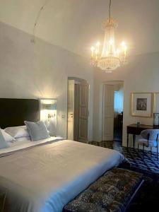 een slaapkamer met een groot wit bed en een kroonluchter bij Suite Vittorio Emanuele in Alba