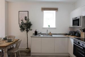 een keuken met witte kasten en een tafel met een plant bij BOURNECOAST - TOWN CENTRE - BEACH 10 min WALK - GARDEN PATIO - 8421 in Bournemouth