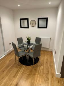 a dining room with a table and chairs and a clock at Colindale luxury Apartment in Colindale +9 photos