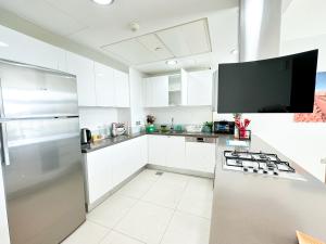 a kitchen with white cabinets and a tv on the wall at The Bay Watchers Abu Dhabi 203NB in Abu Dhabi