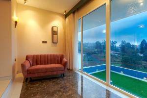 a chair in a room with a large window at Clouds Nest By Aanvis Inn in Ooty