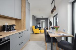 a kitchen and dining room with a table and yellow chairs at Air-Conditioned Seaside Apartment with Parking & Balcony by Renters in Ustronie Morskie