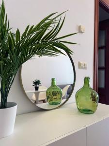 a round mirror on a counter with two green vases at Comodidad en el Centro de Haro in Haro