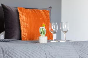 a bed with two wine glasses and a cactus on a table at Air-Conditioned Seaside Apartment with Parking & Balcony by Renters in Ustronie Morskie