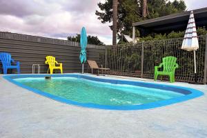 ウェスト・ワイアロングにあるCountry Roads Motor Innのスイミングプール(椅子、パラソル、テーブル付)