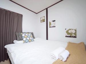 a bedroom with a white bed with towels on it at Nippori Osaka Nishi-Tengachaya Guesthouse西天下茶屋アパートメント in Osaka