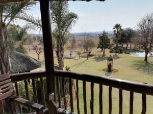 a balcony with a view of a park with palm trees at Kwena Maribane Lodge in Bronkhorstspruit
