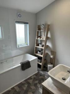 Baño blanco con bañera y lavamanos en Modern Lodge with Amazing Views en Newquay