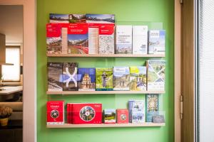 a book shelf filled with books on a green wall at Luna Nuova in Tirano