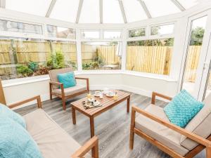 a conservatory with chairs and a table in a room with windows at The Orange Tree Thornham in Thornham