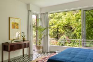 1 dormitorio con cama azul y ventana grande en La Soria Estate en Assagao