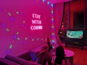 a group of people sitting in a room with a pink wall at KL Gateway Penthouse w Karaoke by Cobnb in Kuala Lumpur