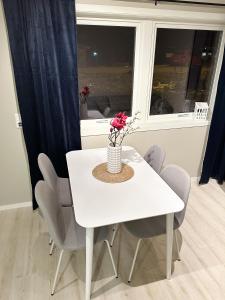 Biały stół jadalny z krzesłami i waza z kwiatami w obiekcie Tromsdalen Aurora Apartments w mieście Tromsø