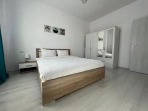 a white bedroom with a large bed and a dresser at VISAJ Metropolitan - authorized by the Ministry of Tourism in Giroc