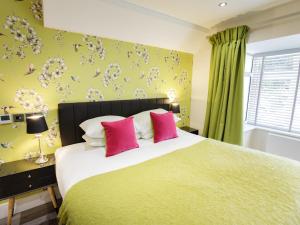 a bedroom with a large bed with two pink pillows at The Orange Tree Thornham in Thornham