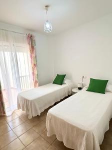 Habitación con 2 camas, sábanas blancas y almohadas verdes. en Apartamento E&D, en Nerja