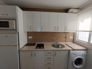 una pequeña cocina con armarios blancos y fregadero en Villablanca Apartamento, en Chipiona