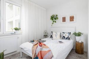 a white bedroom with a bed and a window at Apartment with Balcony + Private parking / Bagry Lake in Krakow