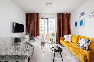 a living room with a yellow couch and a table at Apartment with Balcony + Private parking / Bagry Lake in Krakow