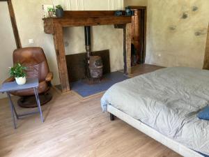 - une chambre avec un lit et une cheminée avec une chaise dans l'établissement Les toits de Miramont, à Montesquieu-Avantès