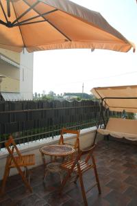 patio z 2 krzesłami, stołem i parasolem w obiekcie Sole Nascente Apartment w mieście Giardini Naxos