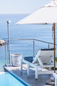 een stoel en een parasol aan de rand van een zwembad bij Clifton Sunset, Does have Power! in Kaapstad