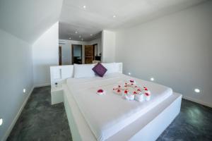 a white bedroom with a white bed with red roses on it at Beachfront Villa Hideaway ZanzibarHouses in Kiwengwa
