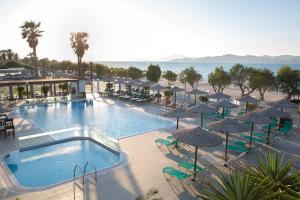 uma piscina com guarda-sóis e cadeiras e a praia em Akti Dimis Hotel em Tigaki