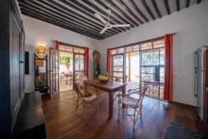 een eetkamer met een tafel en stoelen en een aantal ramen bij Beachfront Villa Hideaway ZanzibarHouses in Kiwengwa