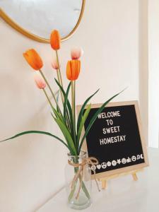 eine Vase mit Blumen auf einem Tisch neben einem Schild in der Unterkunft Sweet Homestay in Port Dickson