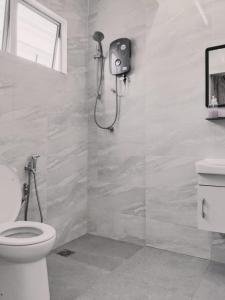 La salle de bains blanche est pourvue d'une douche et de toilettes. dans l'établissement Sweet Homestay, à Port Dickson